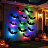 Eine Wand mit leuchtenden schwarzen Fledermaus-Silhouetten in verschiedenen Farben vor einem dunklen Außenbereich.