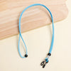 Lanyard bleu vif ajustable pour fixer des lunettes, présenté sur une surface en bois.