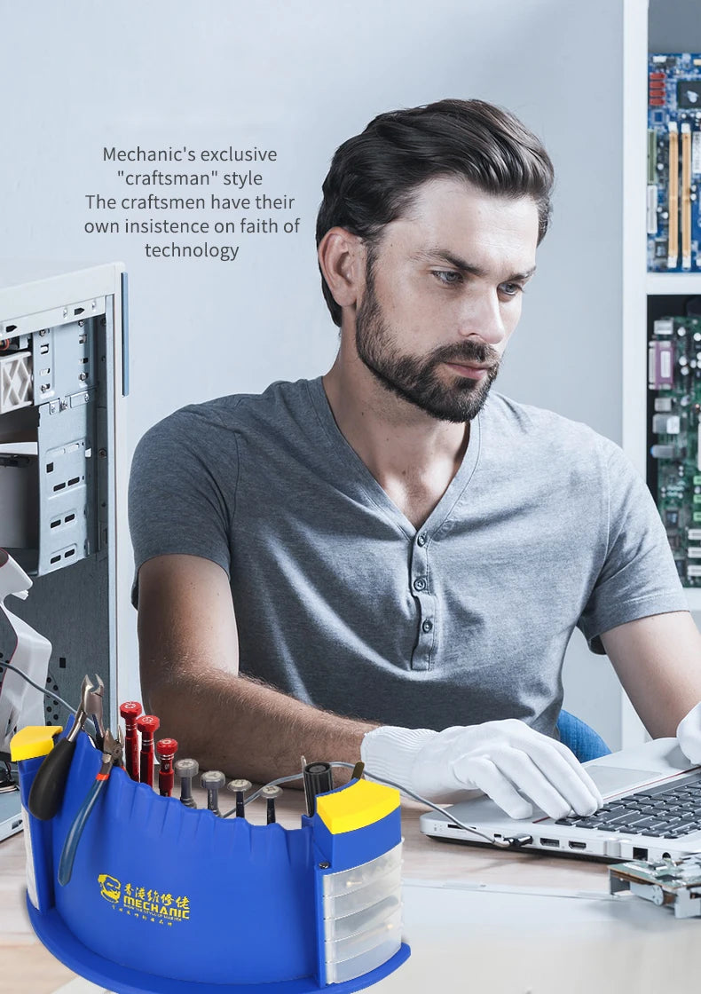 Mann arbeitet an einem Laptop mit einer blauen Aufbewahrungsbox für professionelle Reparaturwerkzeuge und verschiedenen Werkz