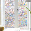 A window covered with a decorative privacy film featuring iridescent, multicolored, abstract patterns.