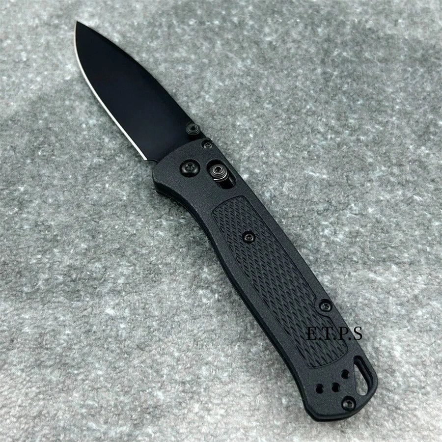 Un couteau EDC pliable noir avec tang complet et poignée texturée, sur fond gris.