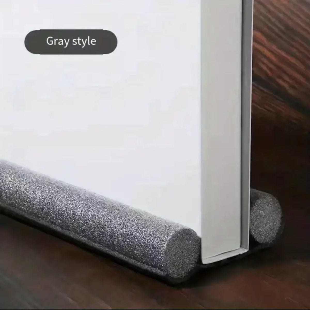 A gray style door and window sealing strip is shown in profile against a dark wooden background.