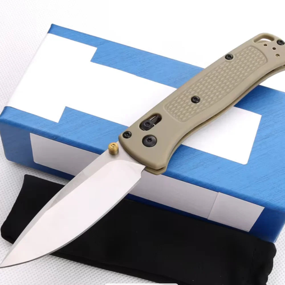 Un couteau pliable beige clair posé sur une boîte bleue avec un design blanc et une gaine noire.