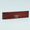 A wooden acoustic guitar bone bridge saddle with the inscription Guyker 4630