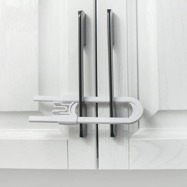 A close-up of adjustable cabinet safety locks installed on a white wooden door frame.