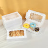White decorative gift boxes containing various baked goods like donuts and pastries.