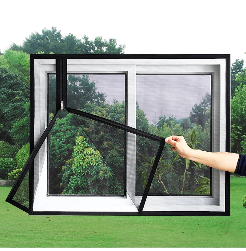 A hand is adjusting a black mesh window screen with a self-adhesive zipper in a white frame against a green outdoor backgroun