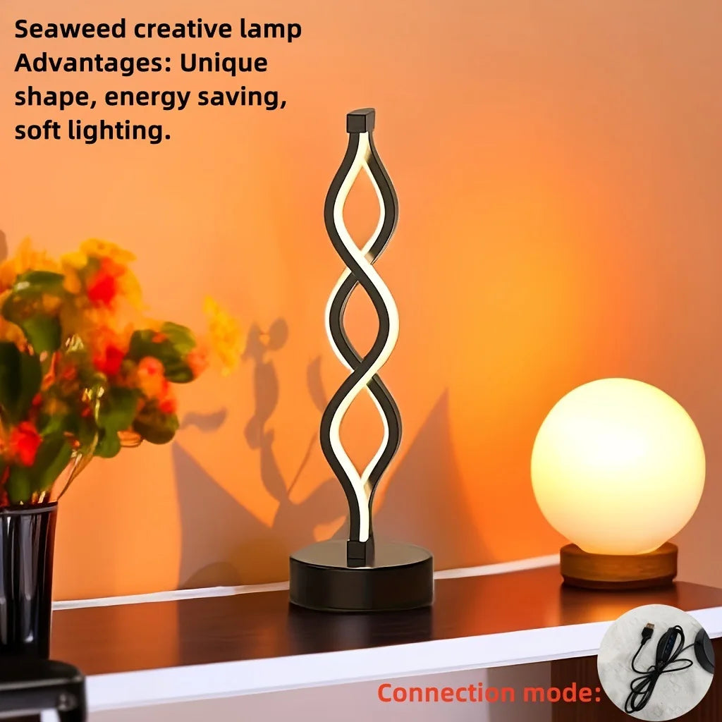 A black and white wavy seaweed creative desk lamp illuminating a round light bulb on a wooden surface.