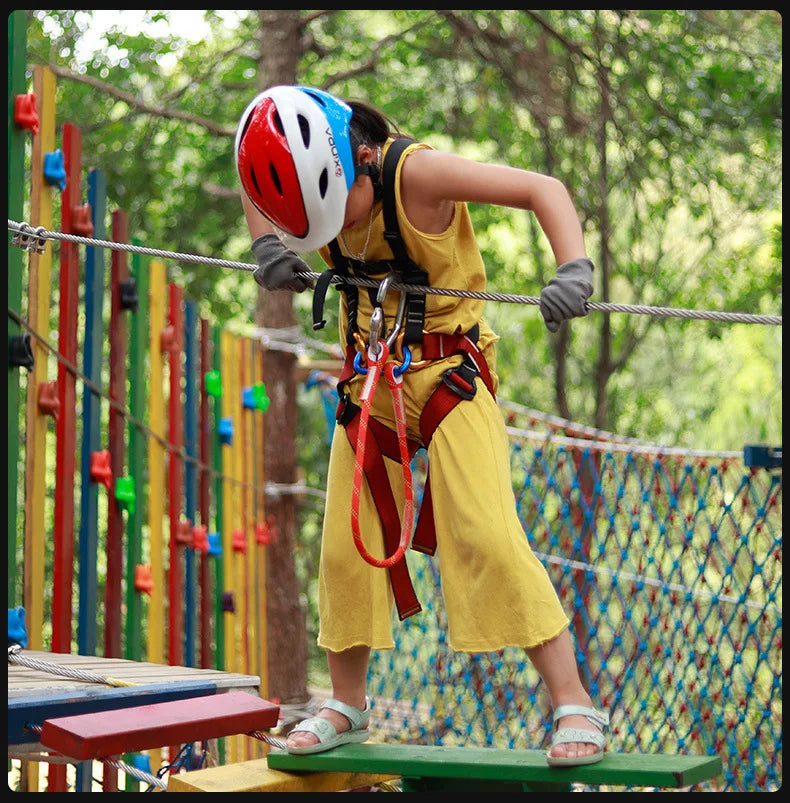 Une personne portant un casque rouge utilise une sangle de corde à œil en œil pour grimper à l'extérieur.