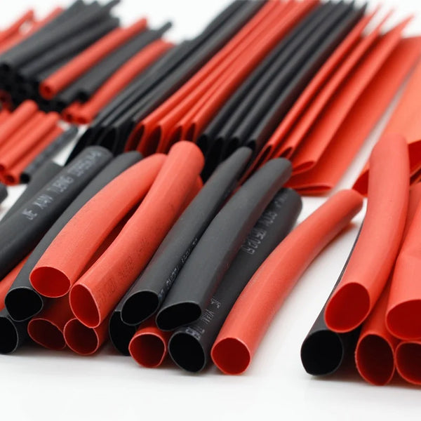 A collection of heat shrink tubing in various shades of red and black, laid out for insulation purposes.