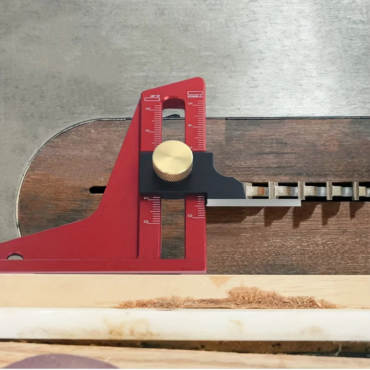 A red precision depth gauge with a brass plunger is shown resting on a wooden surface.