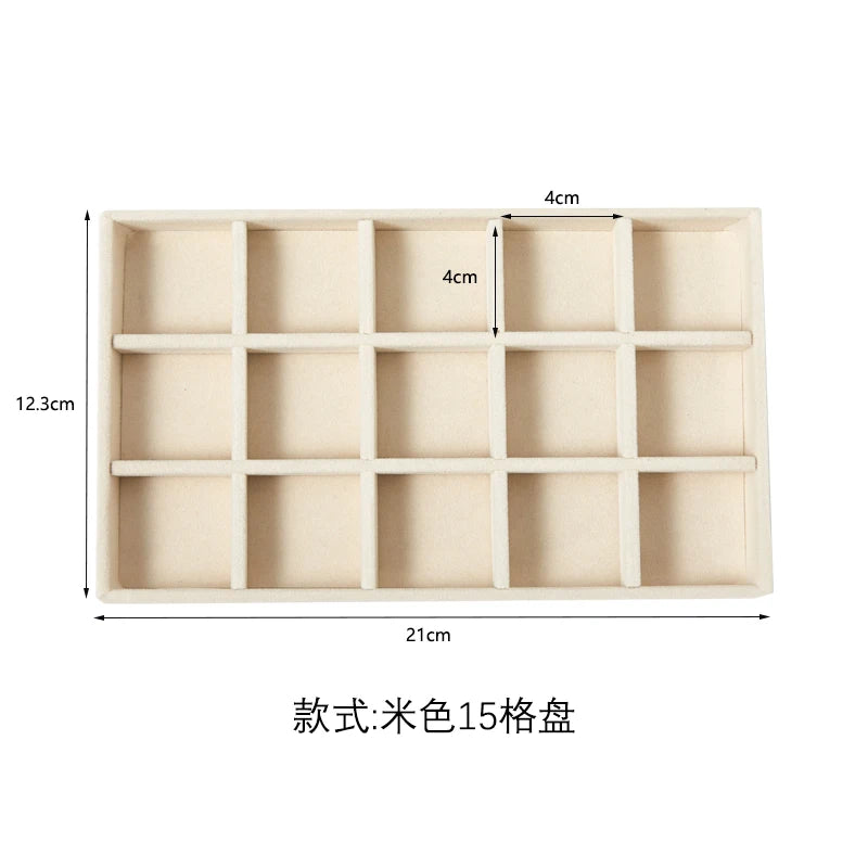 A rectangular light beige jewelry storage tray with 15 compartments for velvet jewelry.