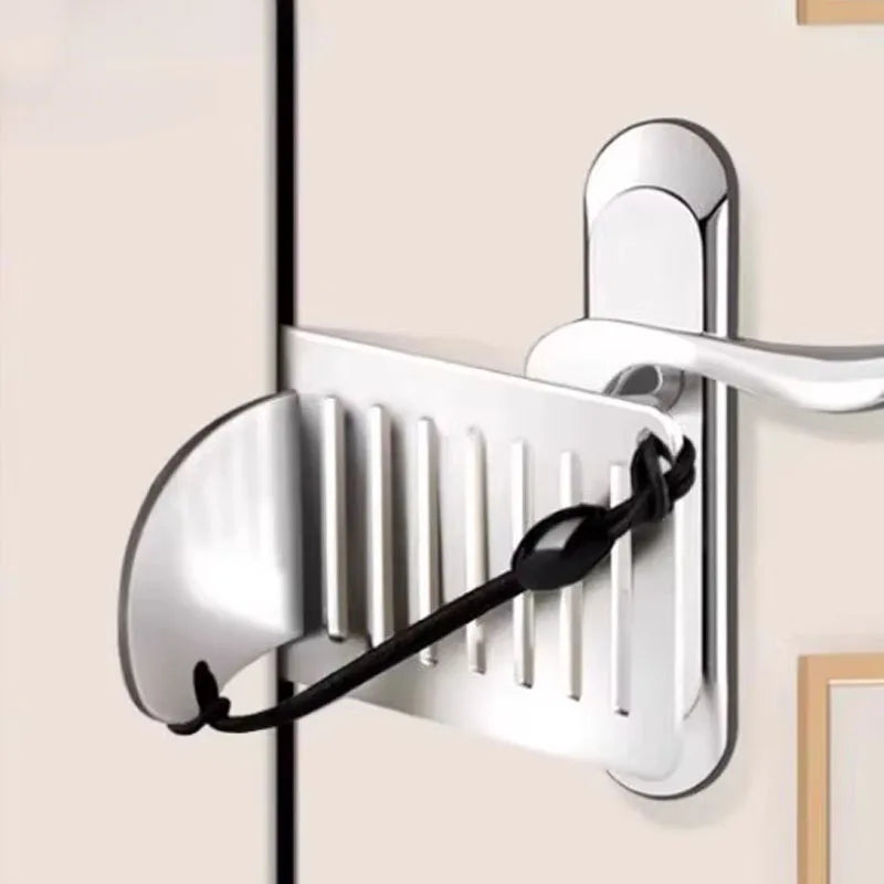 A silver portable door lock with a lever mechanism mounted on a light beige wall.