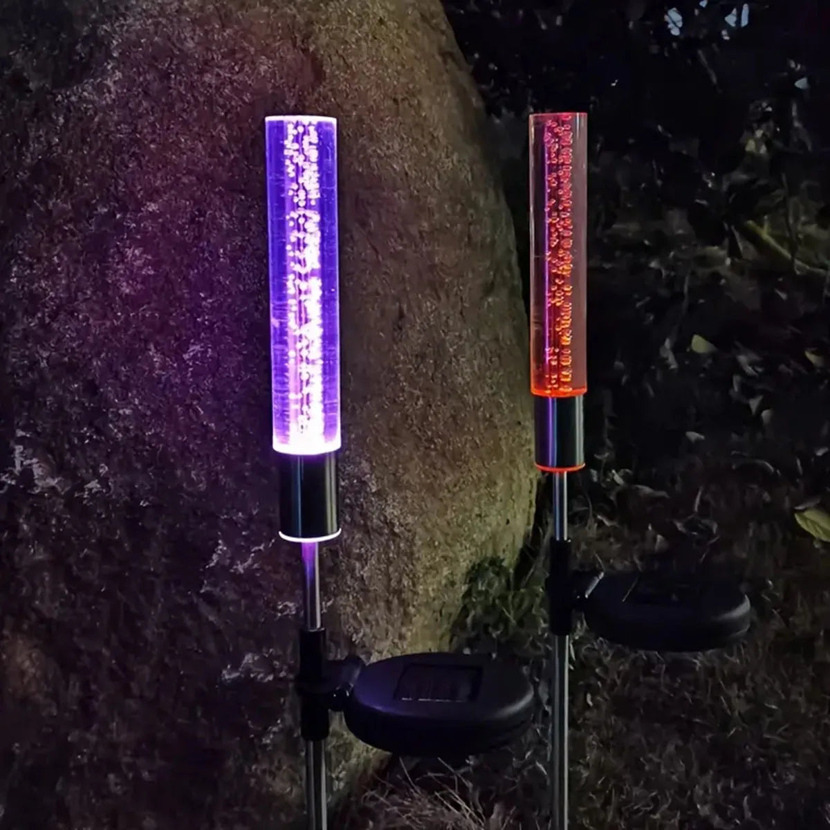Zwei vertikale Solar-LED-Blasenleuchten beleuchten einen dunklen Außenweg.