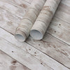 Rolls of retro wood grain self-adhesive wall stickers lying on a weathered white wooden surface.