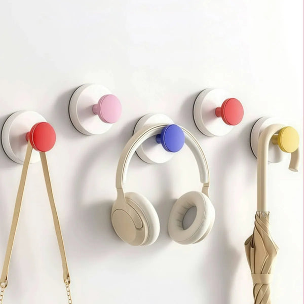 Reusable suction cup hooks in various pastel colors mounted on a white surface.