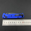 A blue lightweight folding pocket knife is shown next to a ruler for scale.