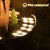 A waterproof LED tree hugging path light illuminates a green fern in the dark.