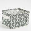 A gray and white patterned foldable linen storage basket with handles.