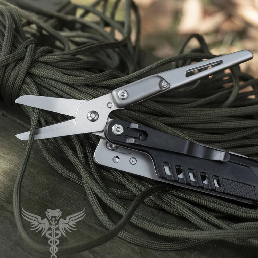 A silver compact multi-tool pocket knife set is shown lying on a dark green cord.