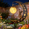 A solar powered owl pathway light shaped like a crescent moon, illuminating a garden setting at night.