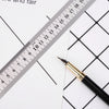A black pen is placed next to a ruler marked in millimeters on white paper.