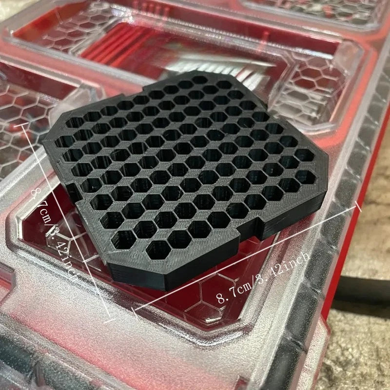 A black hexagonal drill bit organizer insert is shown resting inside a clear red plastic container.