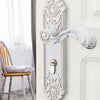 A decorative European style gold door lock with keys mounted on a white wall.