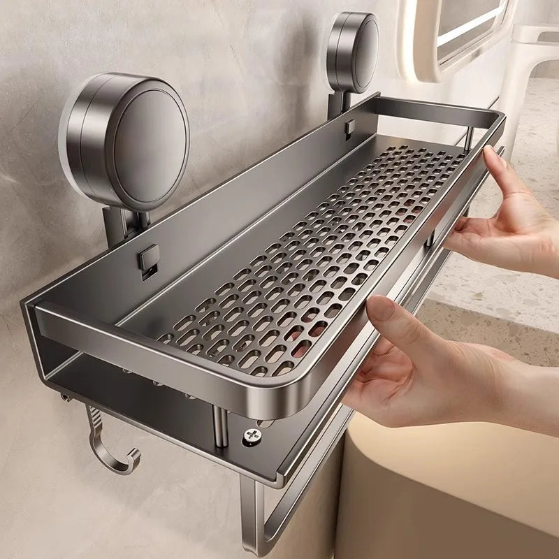 A stainless steel wall mount shower caddy organizer with a grate for holding toiletries is being held by a hand.