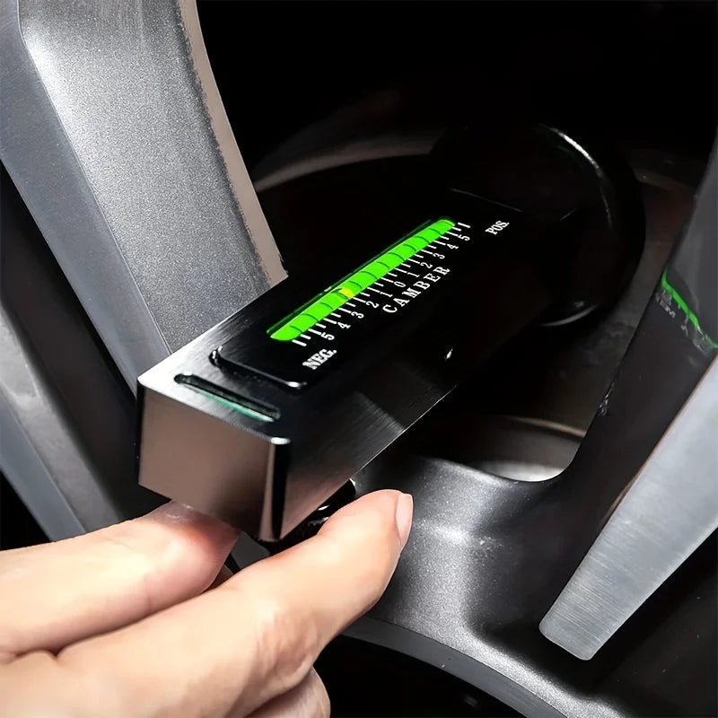 Una mano sostiene una herramienta de alineación ajustable con escala verde dentro del hueco de la rueda de un coche.