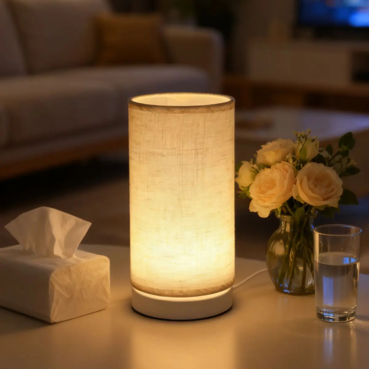 A retro style table lamp with a fabric shade emitting a warm glow on a light-colored surface.