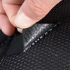 A hand is adjusting heavy duty hook and loop strips on a black fabric surface.