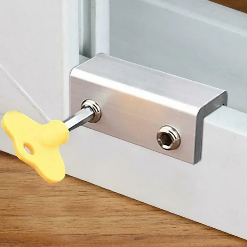 A silver sliding window sash lock stopper with a yellow latch is mounted on a white frame.