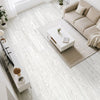 A bright, modern living room featuring light wood grain peel and stick floor tiles, a beige sofa, and a white coffee table.