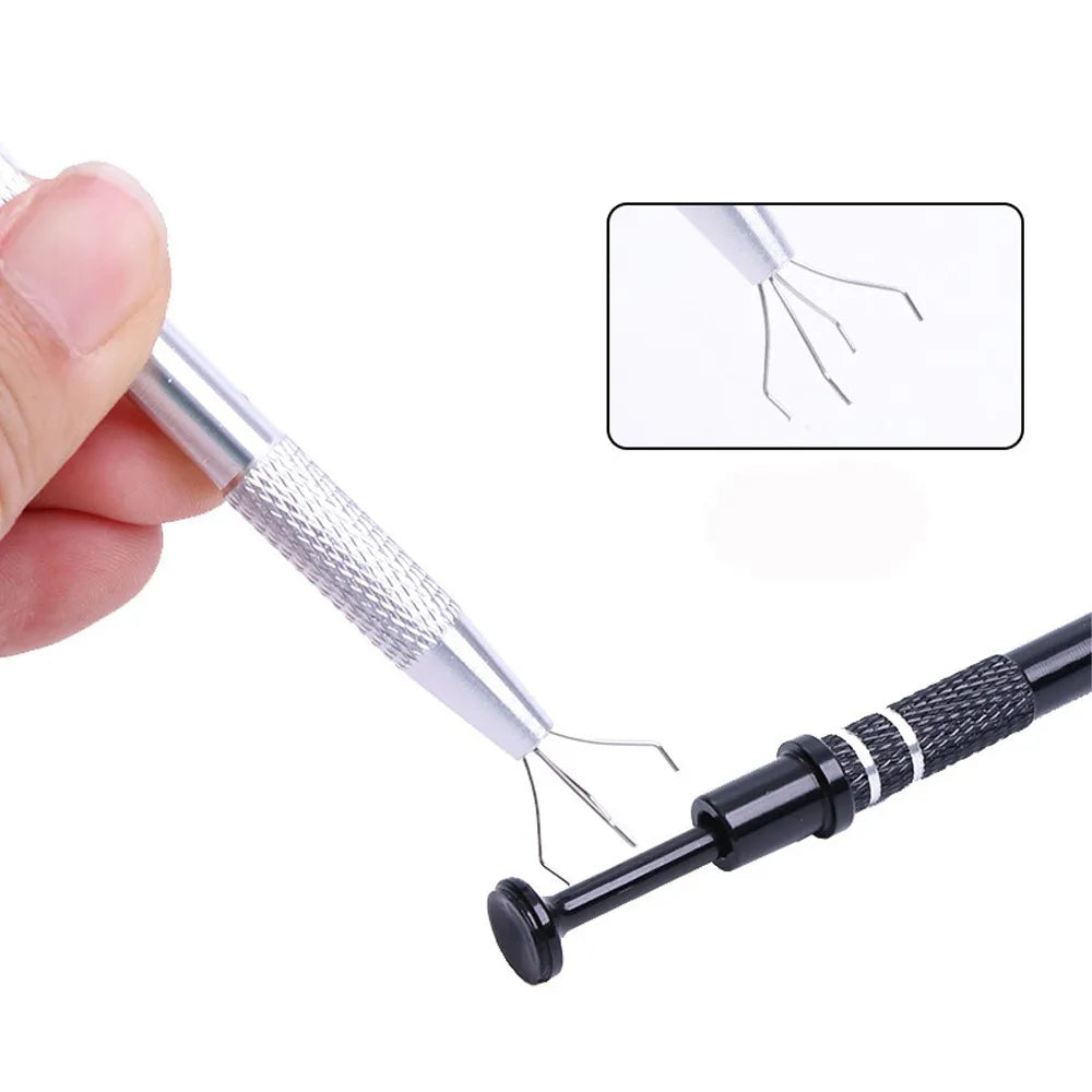 A close-up view of a silver precision tool with four prongs used to grab small parts.