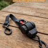 A black auto retractable tie-down strap with a hook and storage mechanism resting on a wooden surface.