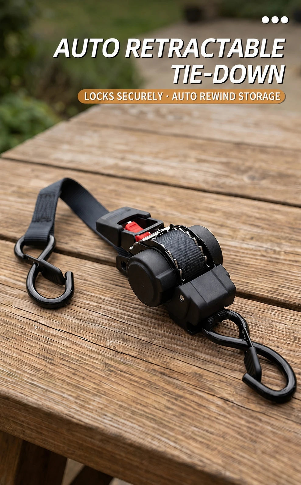 A black auto retractable tie-down strap with a hook and storage mechanism resting on a wooden surface.