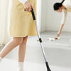 A person is using a foldable silicone garbage grabber tool to pick up items on the floor.