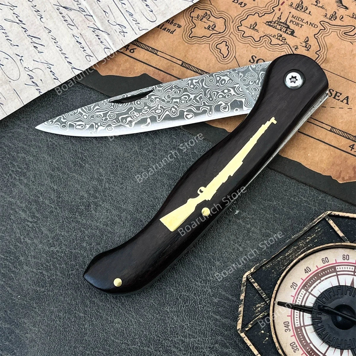 A folding Damascus steel knife with an ebony handle rests on aged parchment paper.