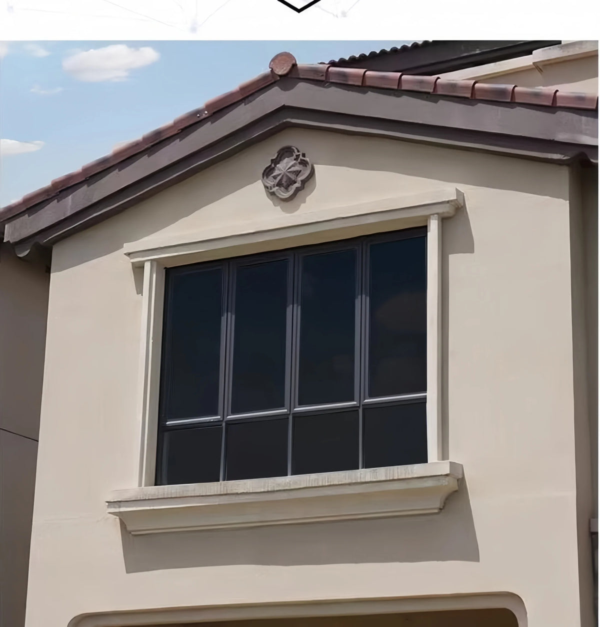 A close-up of a modern house exterior featuring a rectangular window with dark tint film.