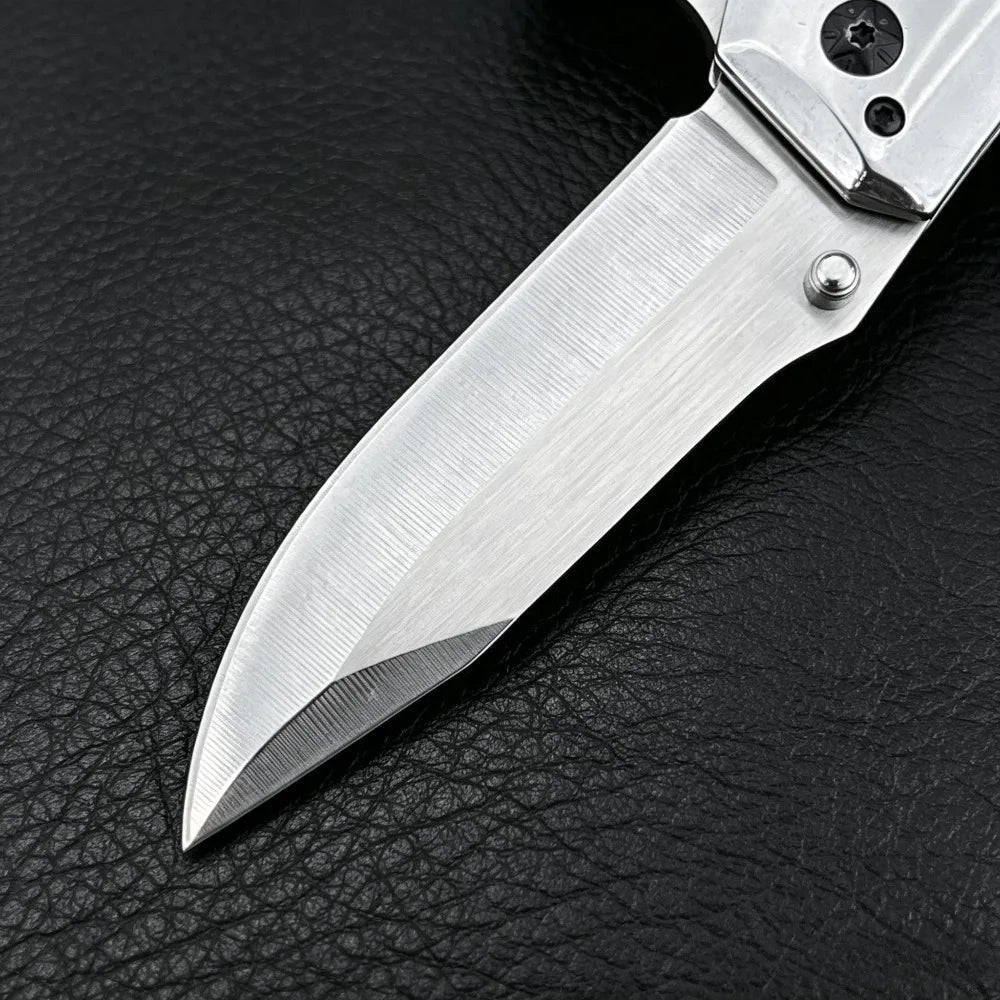 A silver premium folding utility pocket knife blade resting on a black leather surface.