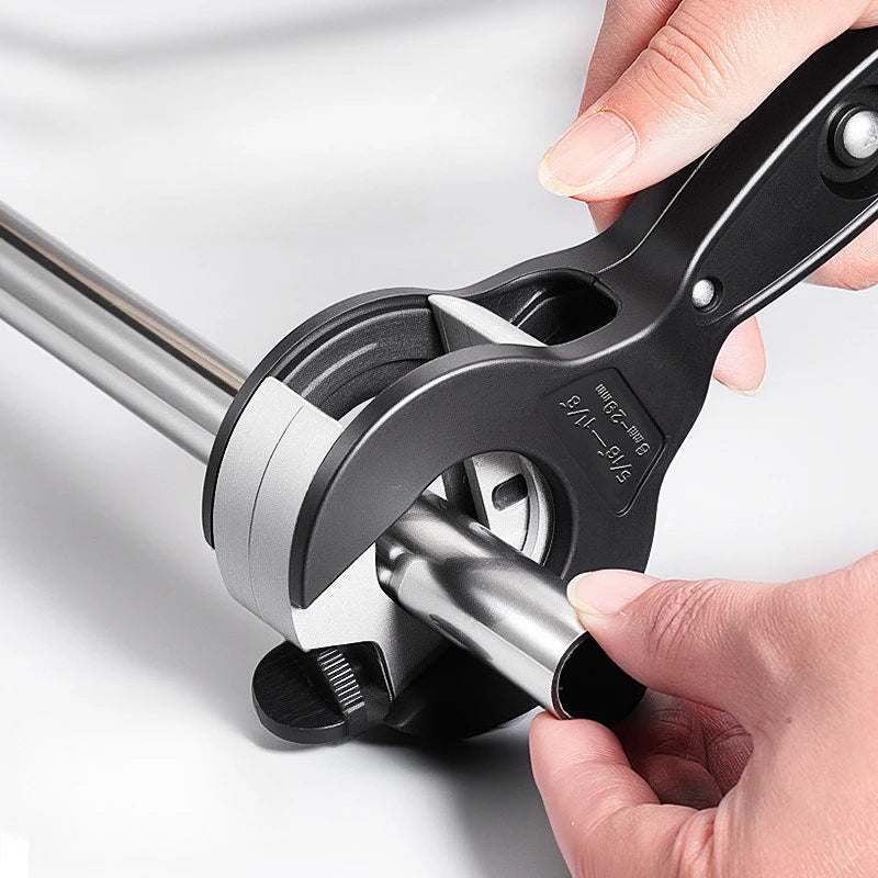 A hand is operating a black precision ratchet pipe cutter, showing the mechanism and cutting tool.