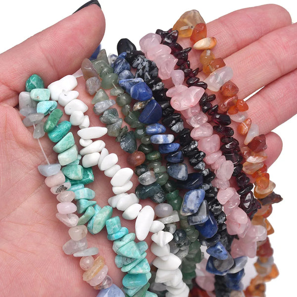 Eine Hand hält mehrere Stränge von Naturstein-Achat-Perlen in verschiedenen Farben wie rosa, blau, grün und Bernstein.