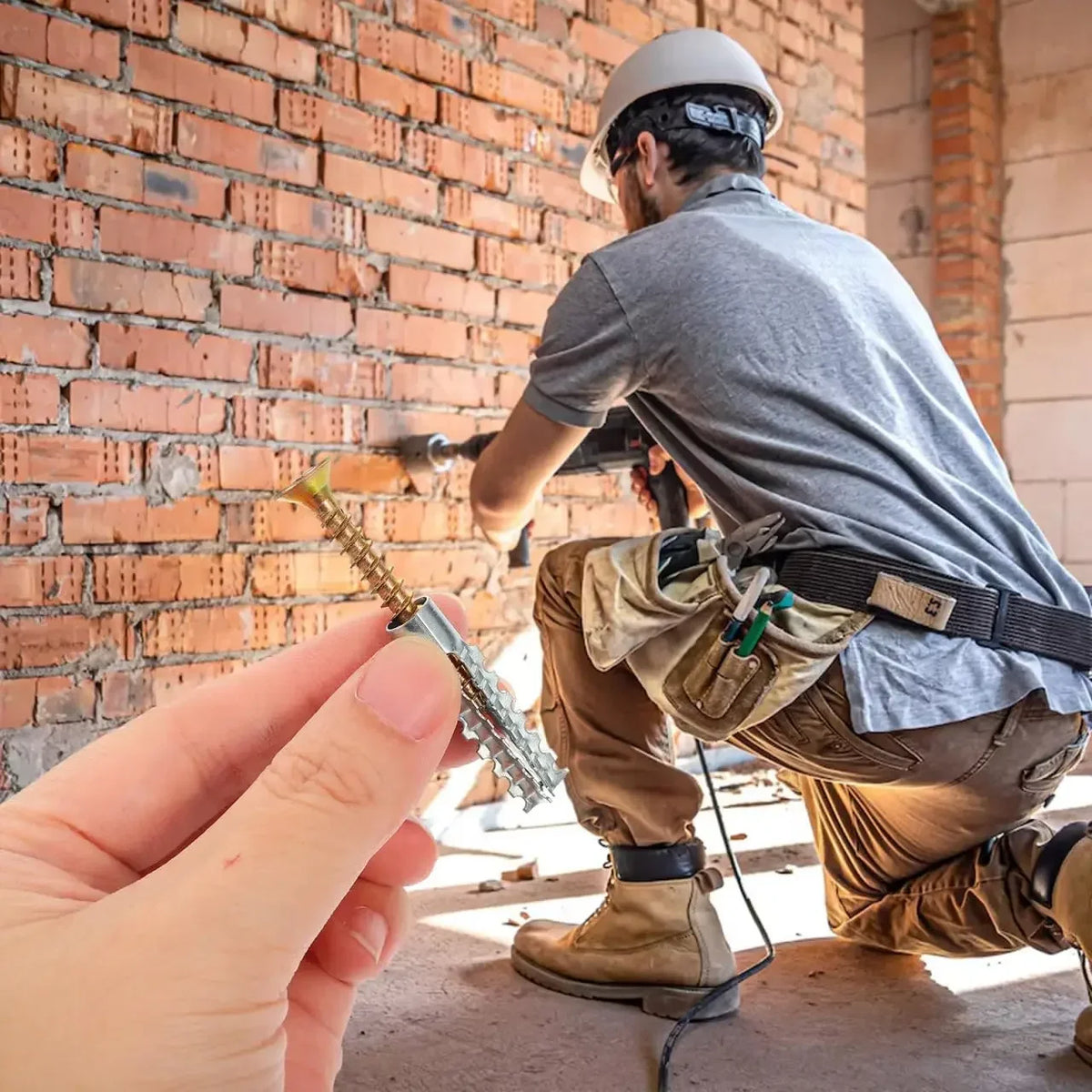 Un homme en chemise grise tient et inspecte des vis d'expansion dentées pour ancrages de béton.