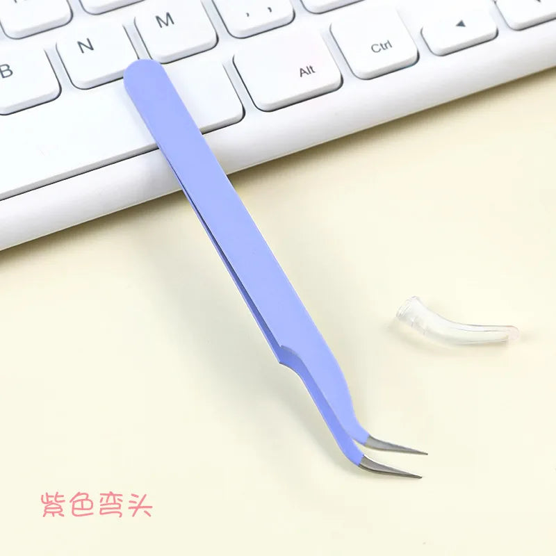 A purple precision crafting tweezers set lying on a white keyboard and light background.