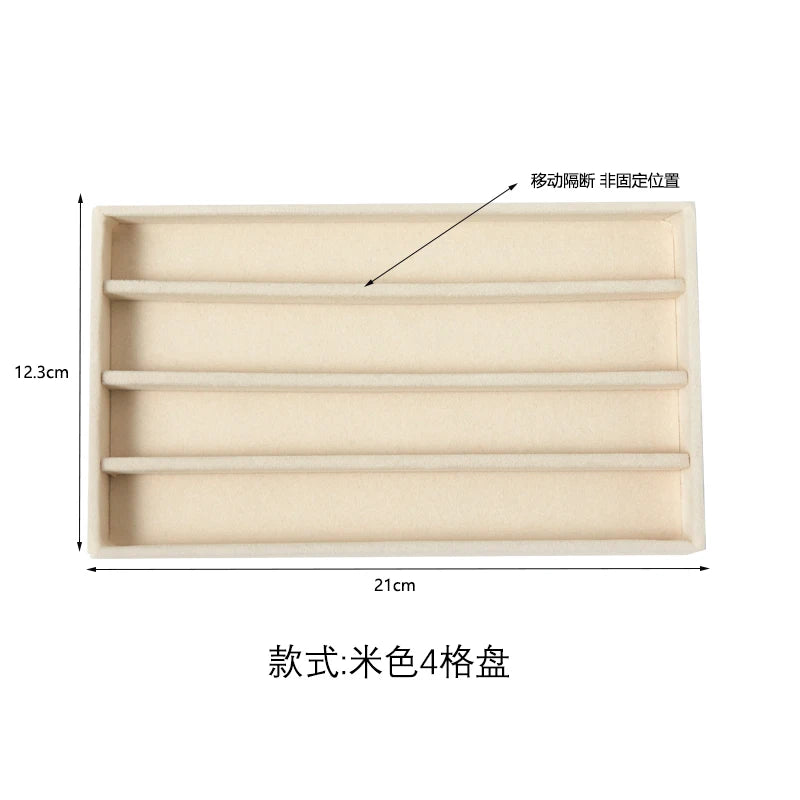 A rectangular beige plush velvet jewelry storage tray with four compartments.