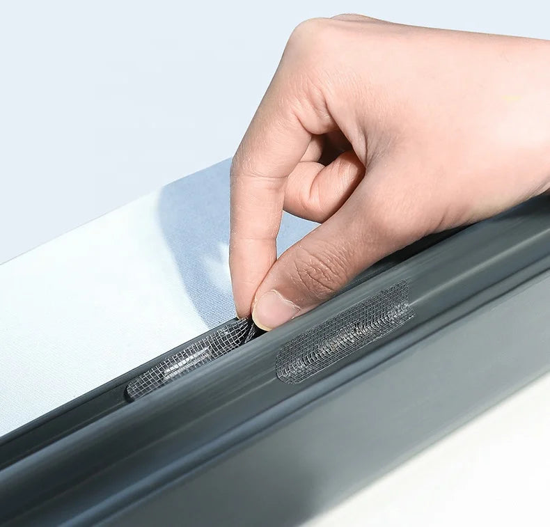 A hand is applying a repair patch to a window screen using a kit.