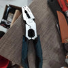 A close-up view of a silver heavy duty wire cutter and stripper tool resting on a wooden surface.