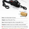 A black auto retractable tie-down strap with various dimensions and features shown against a wooden background.
