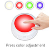 Une main appuie sur un bouton rouge d'un luminaire LED sous le meuble, démontrant l'ajustement de couleur.